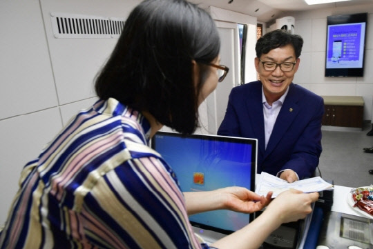 이대훈 농협은행장(오른쪽)이 18일 시연회에서 이동점포에서 금융서비스를 받고 있다.  NH농협은행 제공